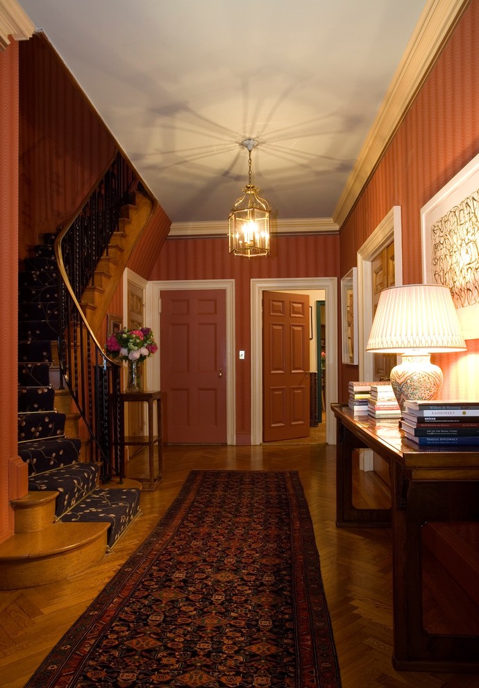 Photo of a mid-sized transitional foyer in New York with multi-coloured walls, light hardwood floors, a single front door and a red front door.