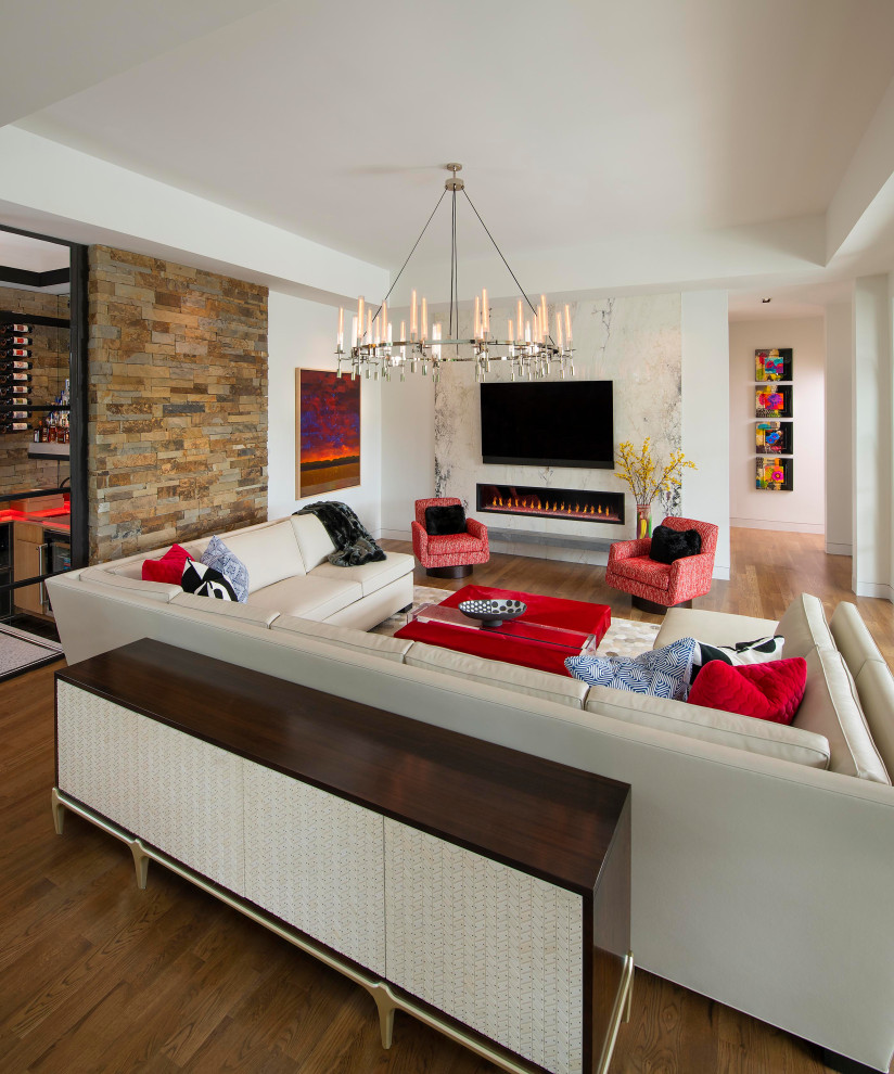 Mittelgroßes, Offenes Modernes Wohnzimmer mit weißer Wandfarbe, braunem Holzboden, Gaskamin, Kaminumrandung aus Stein, TV-Wand und braunem Boden in Dallas