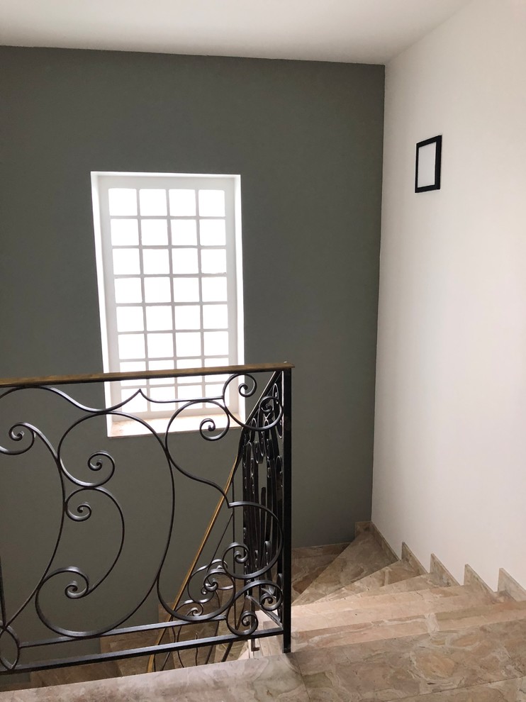 This is an example of a large contemporary marble curved staircase in Paris with marble risers and metal railing.