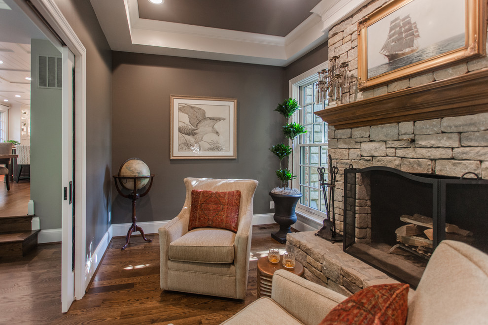 Design ideas for a large transitional study room in Cincinnati with blue walls, dark hardwood floors, a standard fireplace, a stone fireplace surround, brown floor and a freestanding desk.