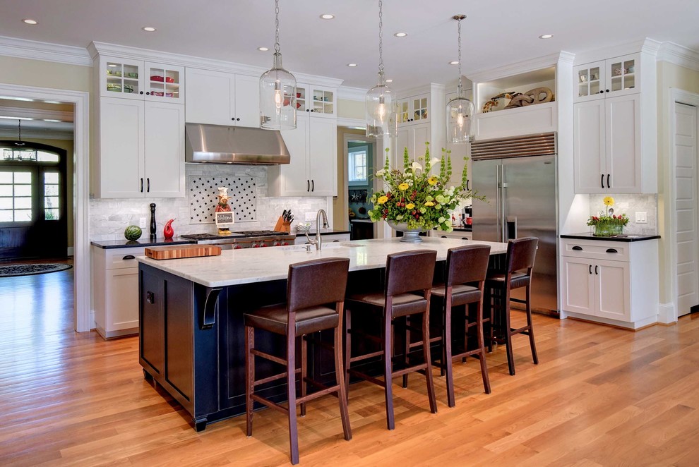 Example of a mid-sized transitional l-shaped medium tone wood floor and brown floor eat-in kitchen design with an undermount sink, shaker cabinets, white cabinets, gray backsplash, subway tile backsplash, stainless steel appliances, an island and soapstone countertops