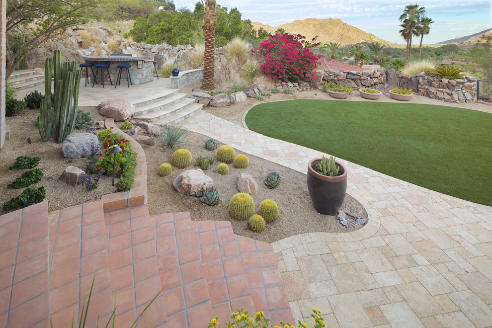 Large mediterranean backyard custom-shaped natural pool in Phoenix with a pool house and natural stone pavers.