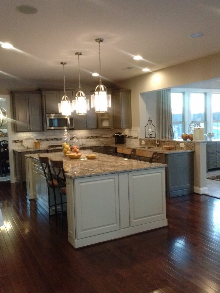 Inspiration for a mid-sized transitional l-shaped medium tone wood floor and red floor eat-in kitchen remodel with an undermount sink, raised-panel cabinets, gray cabinets, granite countertops, multicolored backsplash, subway tile backsplash, stainless steel appliances, an island and multicolored countertops