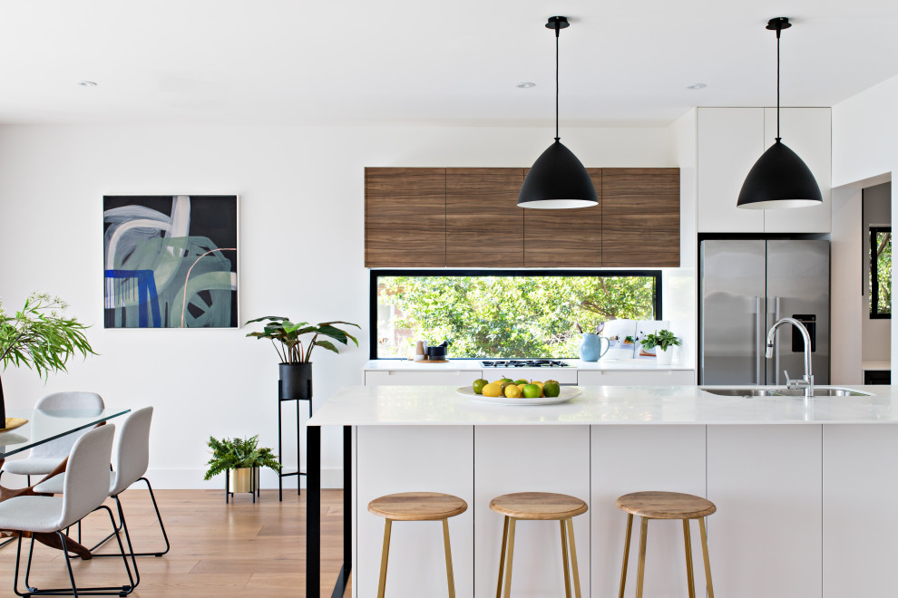 Design ideas for a contemporary galley eat-in kitchen in Sydney with an undermount sink, flat-panel cabinets, white cabinets, stainless steel appliances, medium hardwood floors, a peninsula, brown floor and white benchtop.
