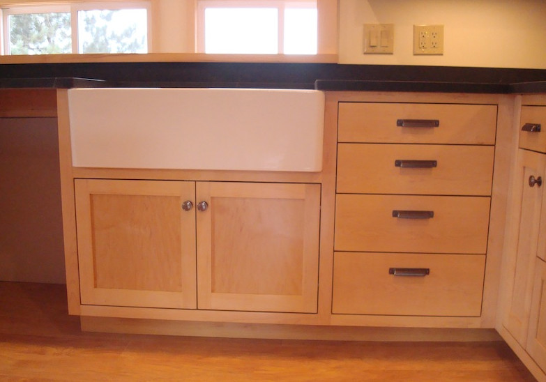 Mid-sized l-shaped medium tone wood floor eat-in kitchen photo with a farmhouse sink, medium tone wood cabinets, solid surface countertops, stainless steel appliances and an island