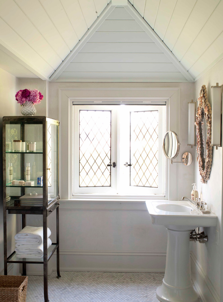 Mid-sized beach style powder room in New York with white floor, white walls, marble floors and a pedestal sink.