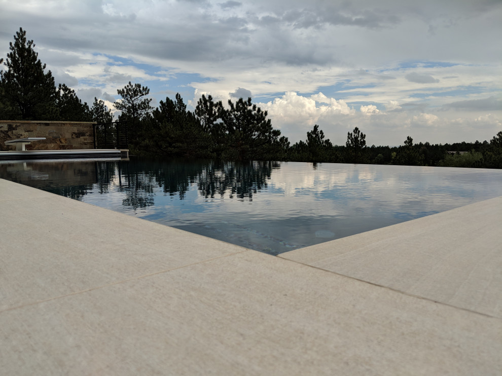 Inspiration for a mid-sized backyard rectangular infinity hot tub remodel in Denver