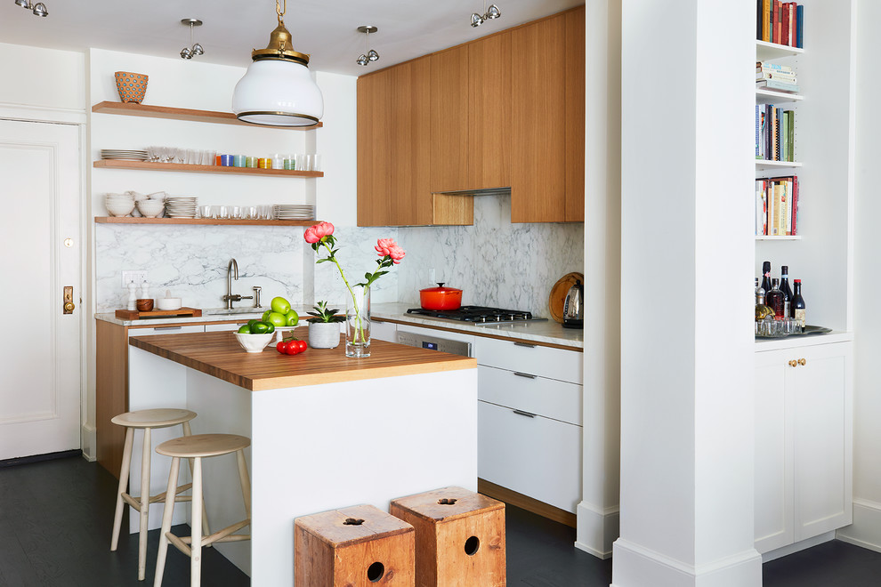 Inspiration for a small contemporary l-shaped open plan kitchen in New York with an undermount sink, flat-panel cabinets, light wood cabinets, wood benchtops, panelled appliances, painted wood floors, with island, white benchtop, grey splashback, marble splashback and black floor.