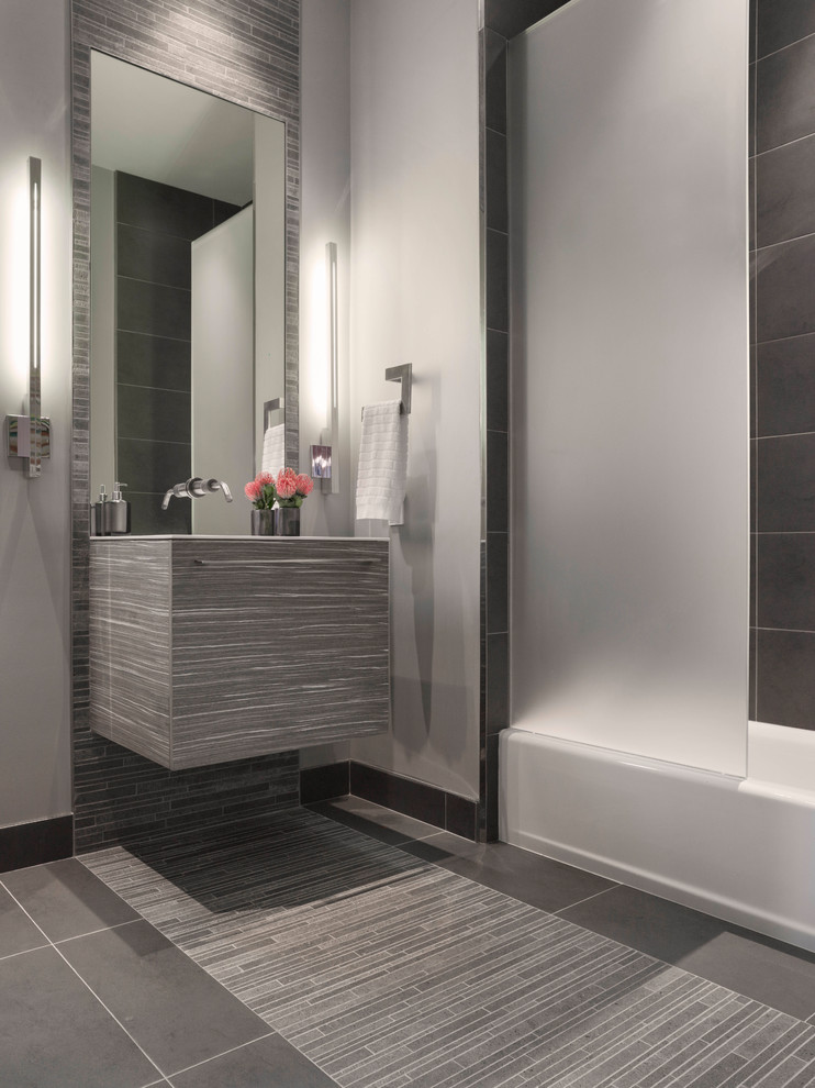 This is an example of a mid-sized modern bathroom in San Francisco with flat-panel cabinets, white cabinets, a one-piece toilet, gray tile, ceramic tile, grey walls, ceramic floors, solid surface benchtops, grey floor, a shower/bathtub combo, white benchtops, an integrated sink, an alcove tub, an open shower, a single vanity and a floating vanity.