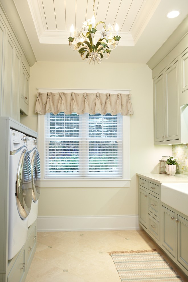 Photo of a traditional laundry room in Grand Rapids with a farmhouse sink, green cabinets, beige walls and beige floor.