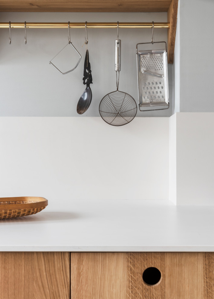 Foto di una cucina lineare scandinava chiusa e di medie dimensioni con lavello a vasca singola, ante a filo, ante in legno chiaro, paraspruzzi bianco, pavimento in cementine, nessuna isola, pavimento marrone e top bianco