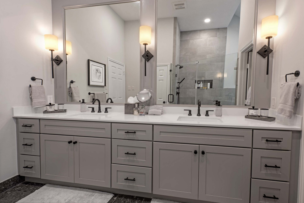 Photo of a large contemporary ensuite wet room bathroom in Houston with shaker cabinets, grey cabinets, a built-in bath, a two-piece toilet, grey walls, ceramic flooring, a submerged sink, engineered stone worktops, black floors, a hinged door, white worktops, a wall niche, double sinks, a built in vanity unit and wainscoting.