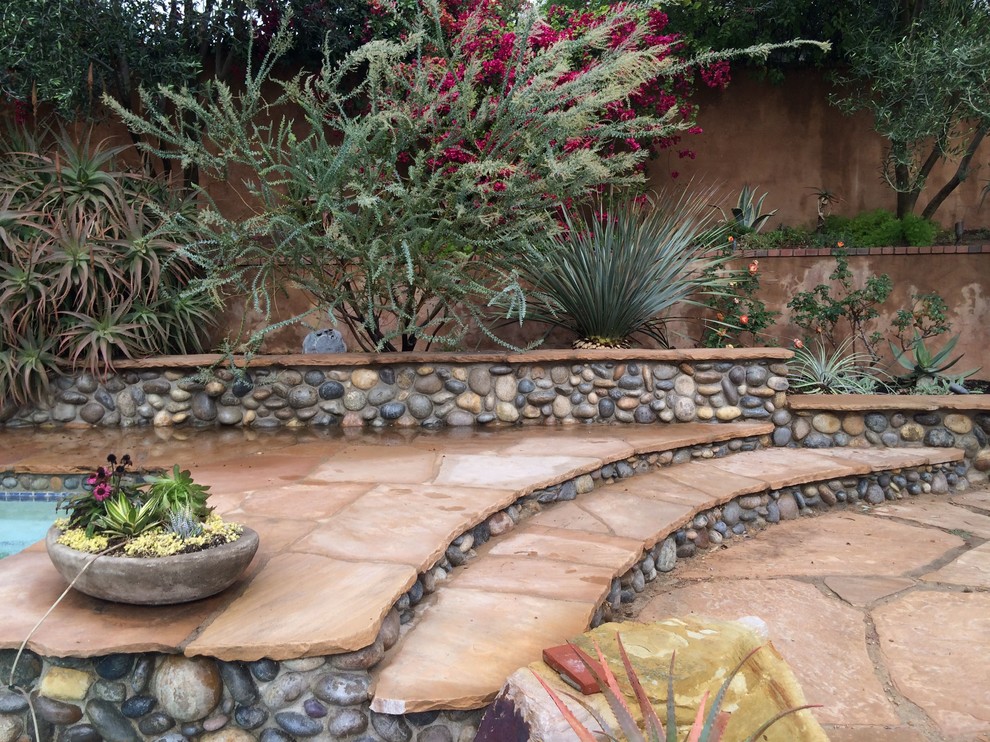 Photo of a large mediterranean backyard full sun xeriscape for summer in Los Angeles with natural stone pavers and a garden path.