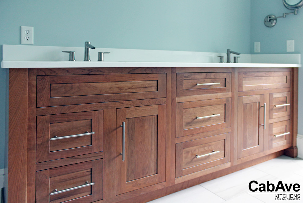 Inspiration for a mid-sized transitional 3/4 porcelain tile and white floor bathroom remodel with recessed-panel cabinets, medium tone wood cabinets, blue walls, an undermount sink and quartz countertops