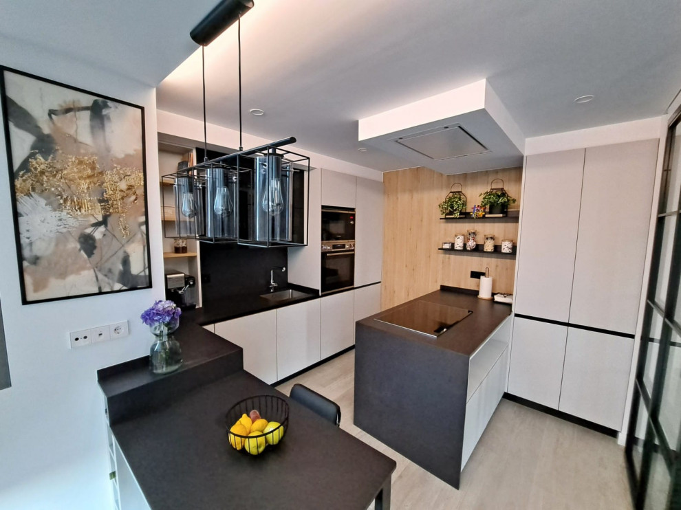 Photo of a medium sized modern grey and black l-shaped open plan kitchen in Other with a submerged sink, flat-panel cabinets, grey cabinets, black splashback, integrated appliances, ceramic flooring, a breakfast bar, grey floors and black worktops.