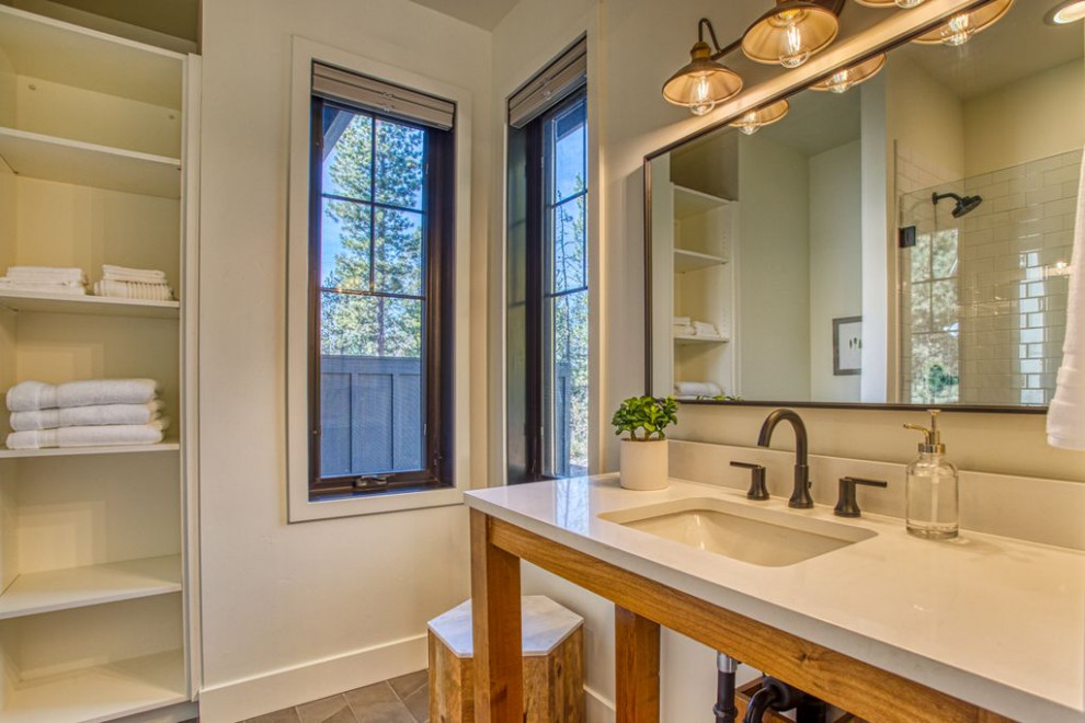 Design ideas for a country 3/4 bathroom in Salt Lake City with open cabinets, light wood cabinets, an alcove shower, a two-piece toilet, subway tile, white walls, an undermount sink, solid surface benchtops, beige floor, a hinged shower door and beige benchtops.