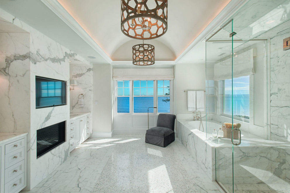 Photo of a large beach style master bathroom in New York with recessed-panel cabinets, white cabinets, an undermount tub, white tile, white walls, white floor, a hinged shower door, marble, mosaic tile floors, an undermount sink, marble benchtops and white benchtops.