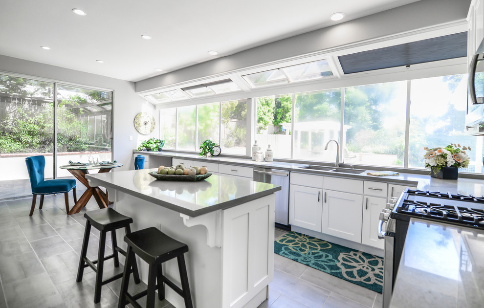 Design ideas for a mid-sized transitional l-shaped eat-in kitchen in Los Angeles with a double-bowl sink, shaker cabinets, white cabinets, solid surface benchtops, stainless steel appliances, cement tiles and with island.