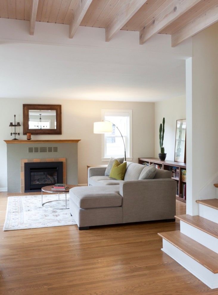 This is an example of a large transitional open concept living room in Seattle with beige walls, light hardwood floors, a standard fireplace, a concrete fireplace surround, no tv and brown floor.