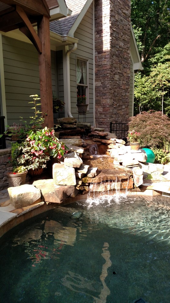 Mid-sized country backyard custom-shaped lap pool in Nashville with a water feature and brick pavers.