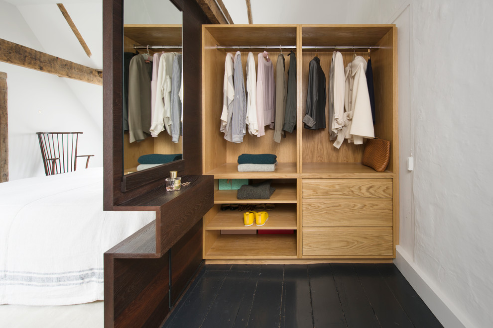 Inspiration for a mid-sized contemporary gender-neutral dressing room in Sussex with painted wood floors, black floor, open cabinets and light wood cabinets.