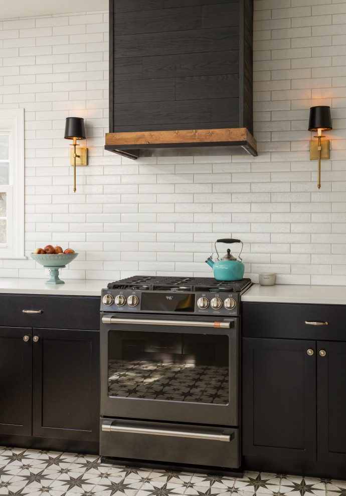 Photo of a large u-shaped open plan kitchen in DC Metro with a drop-in sink, shaker cabinets, black cabinets, quartz benchtops, white splashback, porcelain splashback, black appliances, porcelain floors, a peninsula, multi-coloured floor and white benchtop.