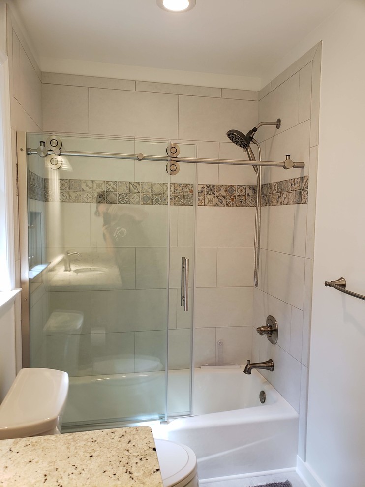 Inspiration for a mid-sized traditional 3/4 bathroom in Raleigh with raised-panel cabinets, medium wood cabinets, an alcove tub, a shower/bathtub combo, a two-piece toilet, white walls, porcelain floors, an undermount sink, granite benchtops, grey floor, a sliding shower screen and multi-coloured benchtops.