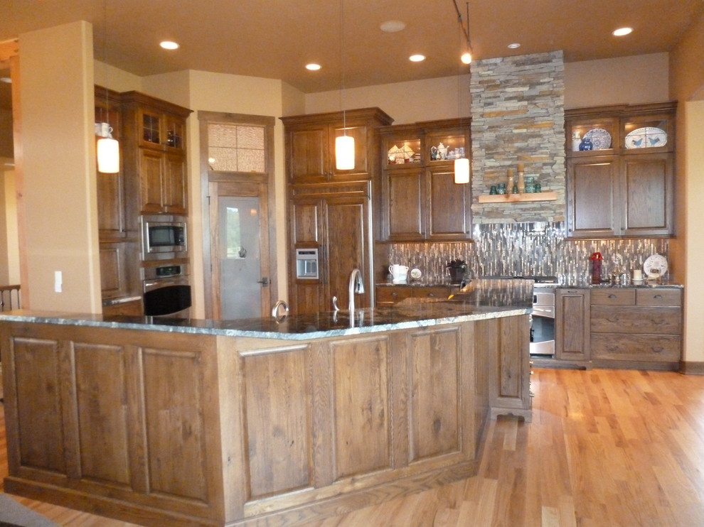 Inspiration for a large rustic l-shaped medium tone wood floor eat-in kitchen remodel with an undermount sink, raised-panel cabinets, dark wood cabinets, granite countertops, multicolored backsplash, matchstick tile backsplash, stainless steel appliances and an island