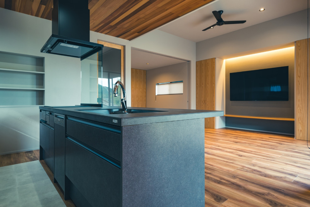 Modern single-wall open plan kitchen in Other with an integrated sink, black cabinets, composite countertops, window splashback, black appliances, medium hardwood flooring, a breakfast bar, brown floors, black worktops and a wood ceiling.