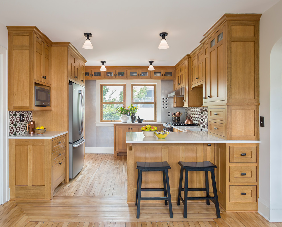 Inspiration for a small arts and crafts u-shaped eat-in kitchen in Minneapolis with an undermount sink, shaker cabinets, light wood cabinets, quartz benchtops, multi-coloured splashback, ceramic splashback, coloured appliances, light hardwood floors, no island, brown floor and white benchtop.