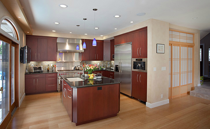 Eat-in kitchen - mid-sized transitional l-shaped light wood floor eat-in kitchen idea with a drop-in sink, medium tone wood cabinets, blue backsplash, stainless steel appliances, an island, flat-panel cabinets, granite countertops and cement tile backsplash