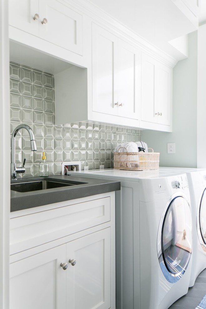 Mid-sized transitional single-wall dedicated laundry room in Orange County with an undermount sink, shaker cabinets, white cabinets, solid surface benchtops, porcelain floors, a side-by-side washer and dryer, grey floor and grey walls.