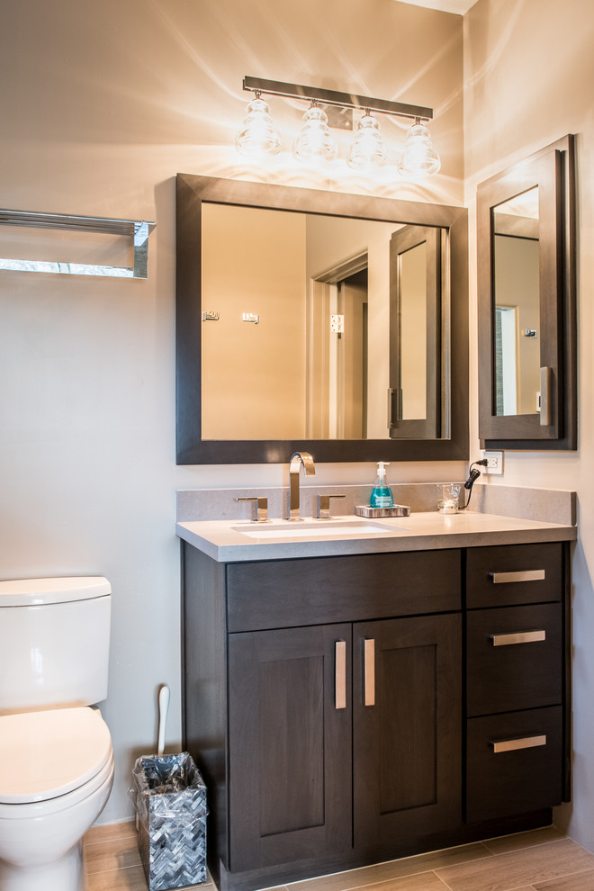 Inspiration for a mid-sized rustic 3/4 porcelain tile and beige floor alcove shower remodel in Phoenix with beige walls, an undermount sink, a hinged shower door, shaker cabinets, dark wood cabinets, solid surface countertops and beige countertops