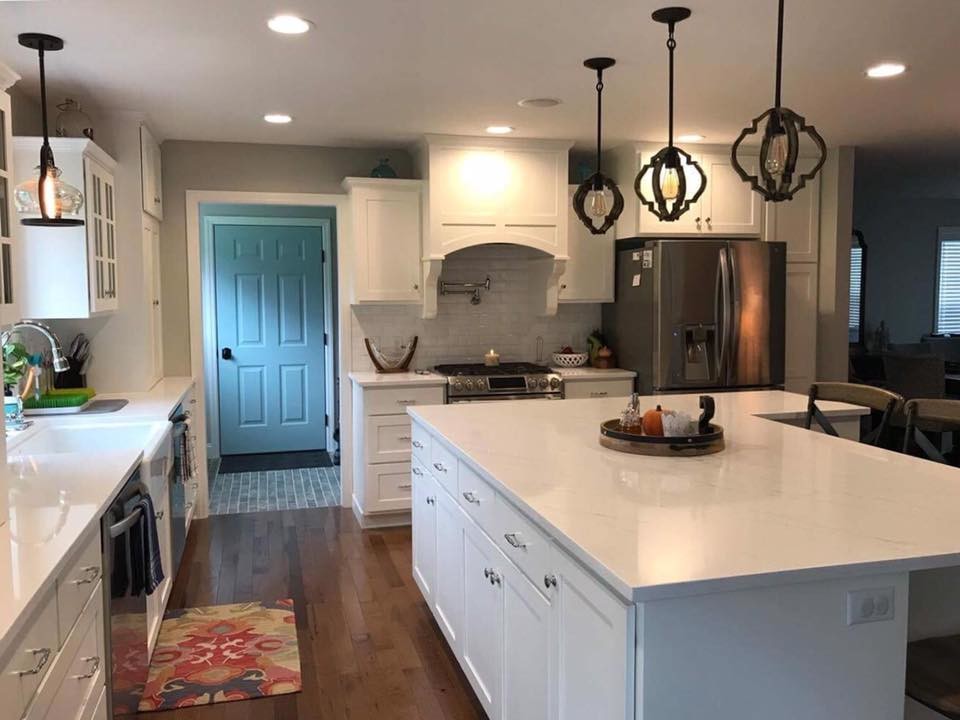 Inspiration for a transitional l-shaped kitchen remodel in Philadelphia with a farmhouse sink, shaker cabinets, white cabinets, marble countertops, white backsplash, subway tile backsplash, stainless steel appliances and an island