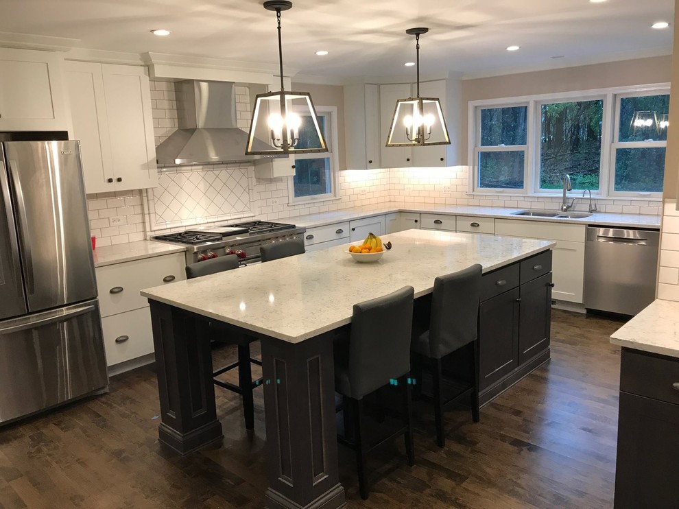 Inspiration for a large transitional u-shaped dark wood floor and brown floor kitchen remodel in Chicago with an undermount sink, shaker cabinets, white cabinets, quartzite countertops, white backsplash, subway tile backsplash, stainless steel appliances and an island