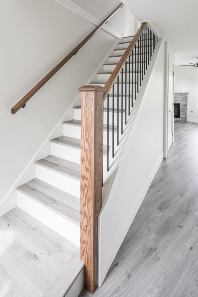 Imagen de escalera recta tradicional renovada con contrahuellas de madera pintada y barandilla de madera