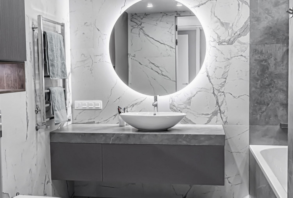 This is an example of a medium sized contemporary grey and white ensuite bathroom in Other with flat-panel cabinets, grey cabinets, a freestanding bath, a wall mounted toilet, grey tiles, porcelain tiles, grey walls, a pedestal sink, engineered stone worktops, grey floors, grey worktops, a single sink and a floating vanity unit.