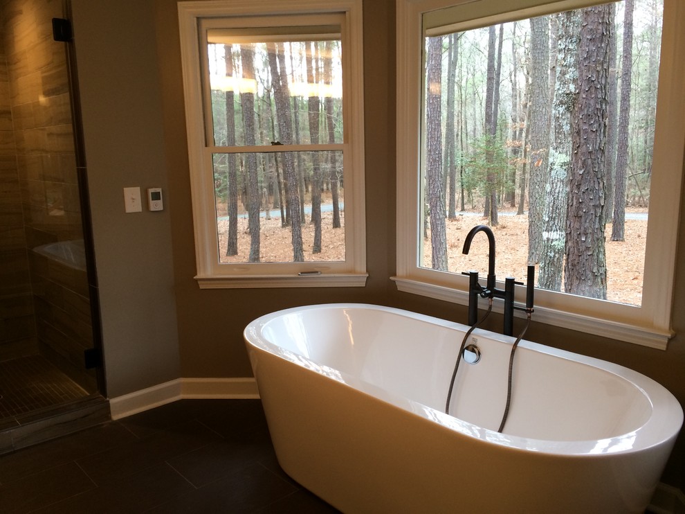 This is an example of a mid-sized modern master bathroom in Raleigh with a freestanding tub, a shower/bathtub combo, brown walls, dark hardwood floors, brown floor and an open shower.