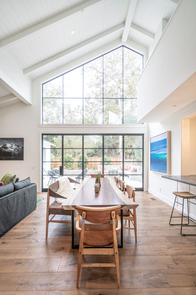 Design ideas for an expansive transitional open plan dining in Santa Barbara with white walls, medium hardwood floors, a standard fireplace, a plaster fireplace surround, brown floor and timber.