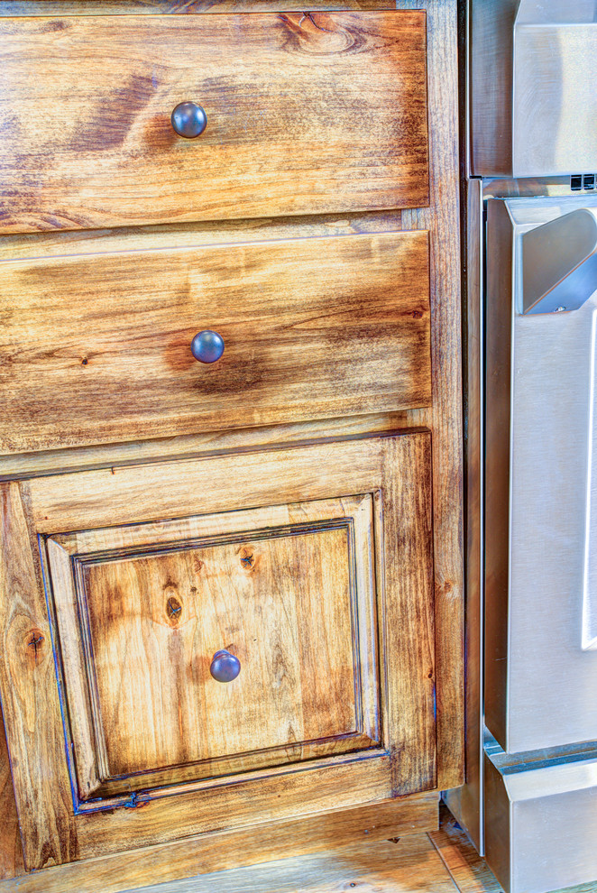 Kitchen pantry - large rustic u-shaped medium tone wood floor kitchen pantry idea with a drop-in sink, glass-front cabinets, medium tone wood cabinets, beige backsplash, stainless steel appliances and an island