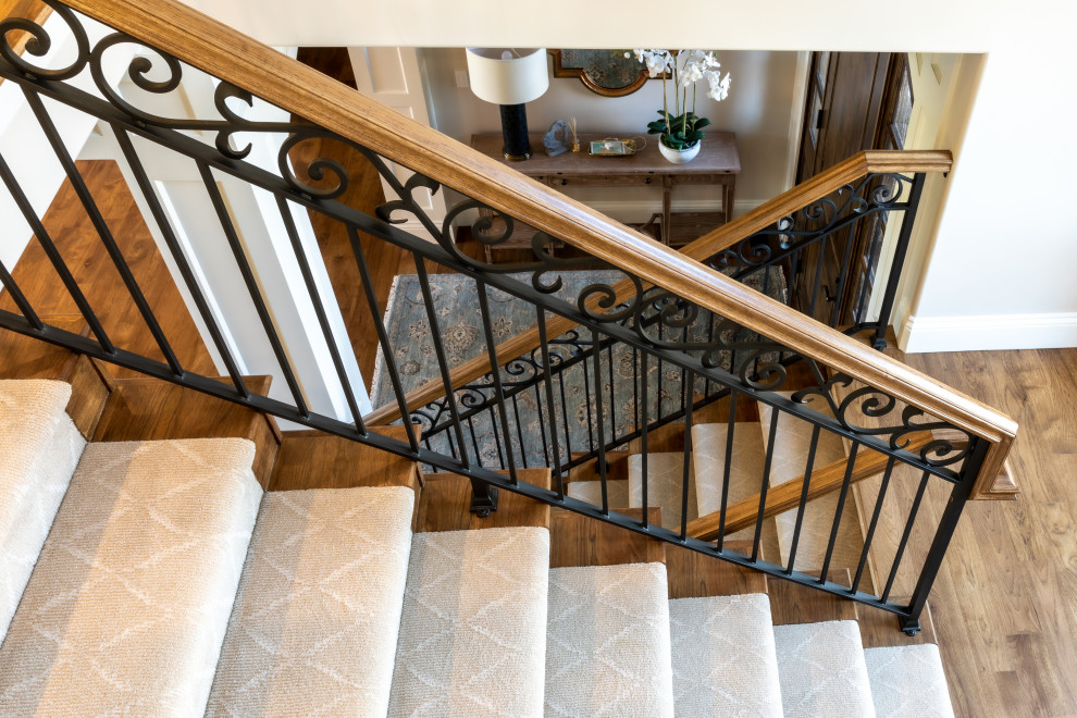 Diseño de escalera en L clásica con escalones de madera, contrahuellas de madera y barandilla de metal