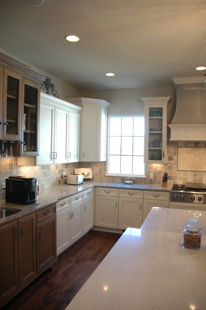 Example of a large transitional u-shaped medium tone wood floor kitchen pantry design with a farmhouse sink, flat-panel cabinets, white cabinets, granite countertops, brown backsplash, stone tile backsplash, paneled appliances and an island