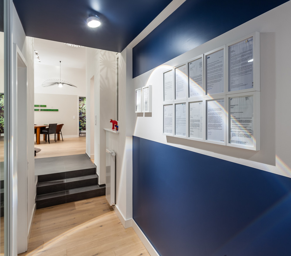 Mittelgroßer Moderner Flur mit blauer Wandfarbe und hellem Holzboden in Köln