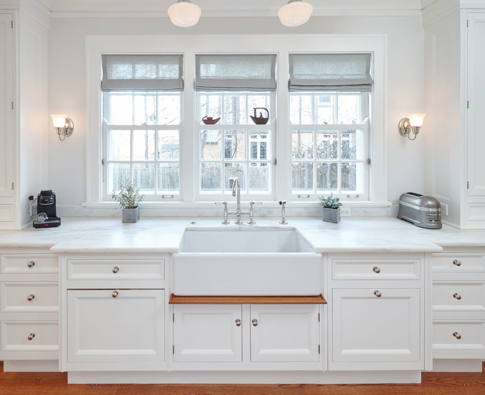 This is an example of a large traditional u-shaped separate kitchen in Chicago with a farmhouse sink, beaded inset cabinets, white cabinets, marble benchtops, green splashback, ceramic splashback, black appliances, medium hardwood floors and with island.