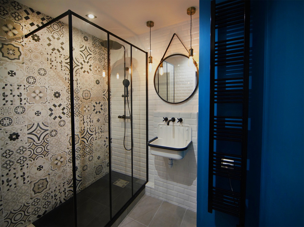 This is an example of a small industrial master bathroom in Paris with a curbless shower, black and white tile, cement tile, blue walls, ceramic floors, a wall-mount sink, tile benchtops, grey floor and white benchtops.