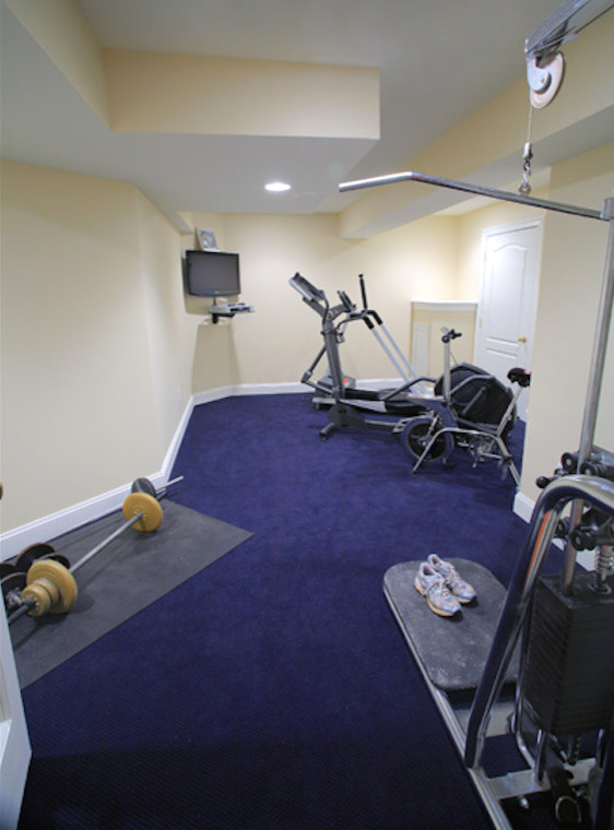This is an example of a traditional home weight room in Philadelphia with beige walls, carpet and blue floor.