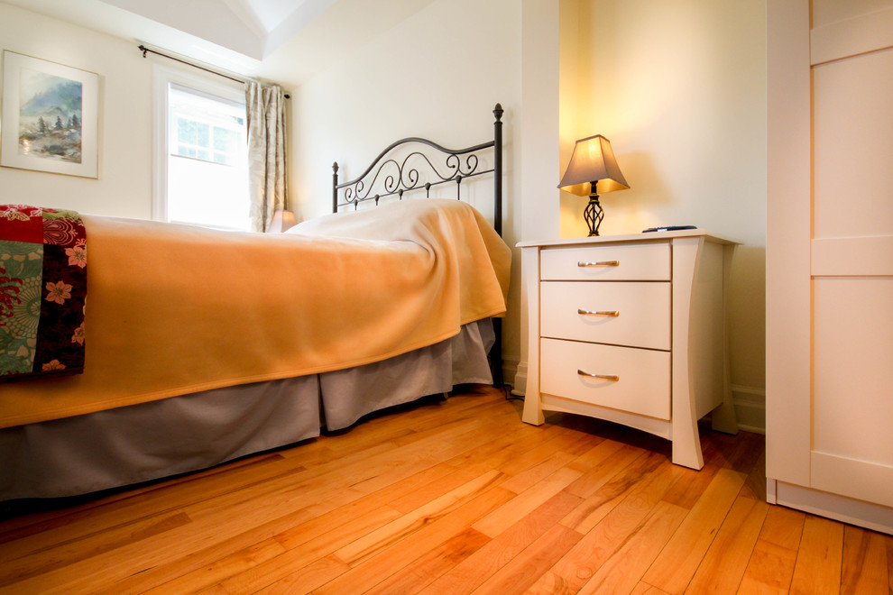 Photo of a mid-sized transitional master bedroom in Ottawa with yellow walls and light hardwood floors.