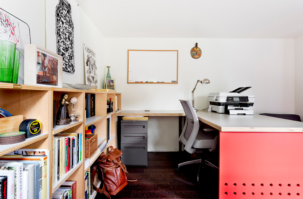 Small modern home office in New York with a library, white walls, dark hardwood floors and a built-in desk.