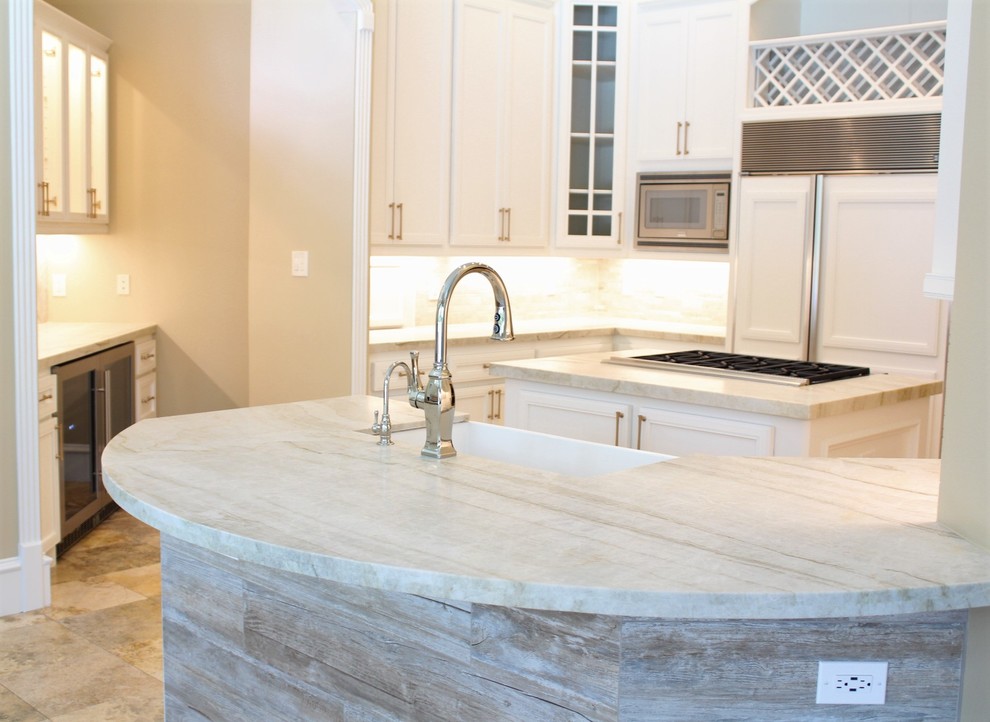 Large transitional u-shaped eat-in kitchen in Houston with a farmhouse sink, recessed-panel cabinets, white cabinets, quartzite benchtops, beige splashback, limestone splashback, stainless steel appliances, travertine floors, multiple islands and beige floor.