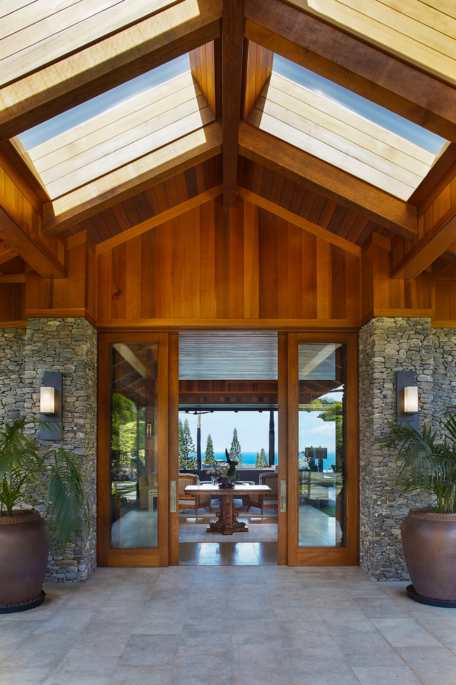 This is an example of a large tropical front door in Hawaii with a sliding front door and a medium wood front door.